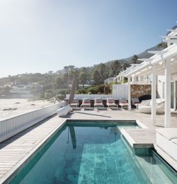 Expansive white villa with vibrant blue pool overlooking blue skies