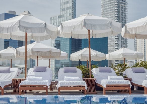 Rooftop swimming pool with sunbeds and skyscrapers in the background