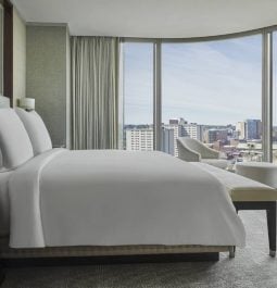 hotel room with white bedding and wall of windows