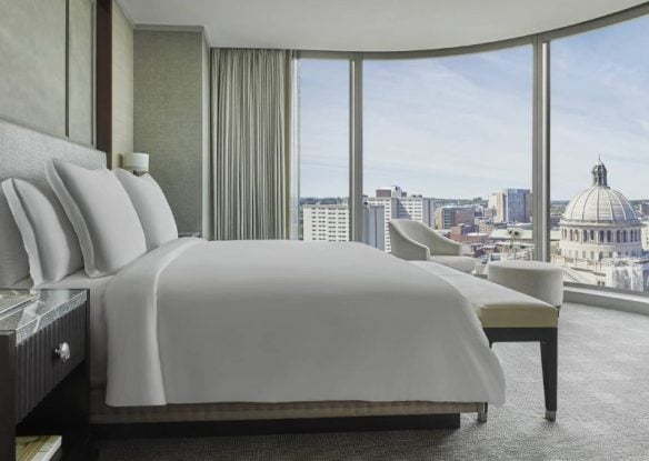 hotel room with white bedding and wall of windows