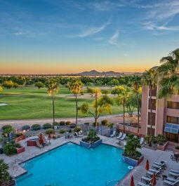 Resort pool and palm trees next to golf course